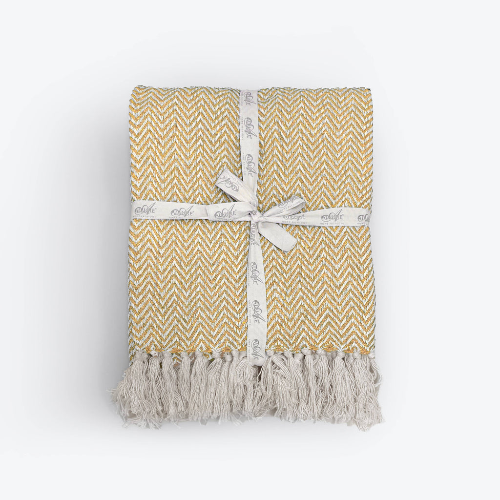 Moorland Herringbone Cotton Throw in Moss laid across a bed, Croft & Cleo