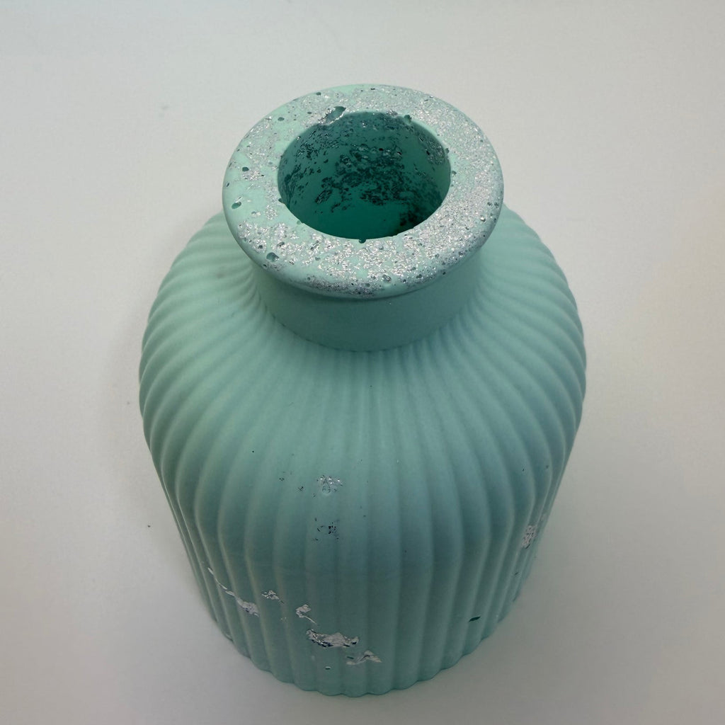 A small ribbed ceramic vase in a light aqua or mint green color with distressed white paint details, shown on a plain white background.