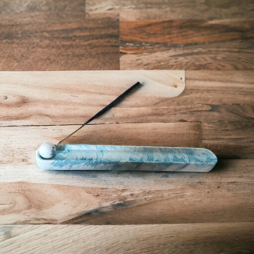 Blue marble Jesmonite incense holder with lit incense stick, angled view showing the marbled surface and wood backdrop, Croft & Cleo