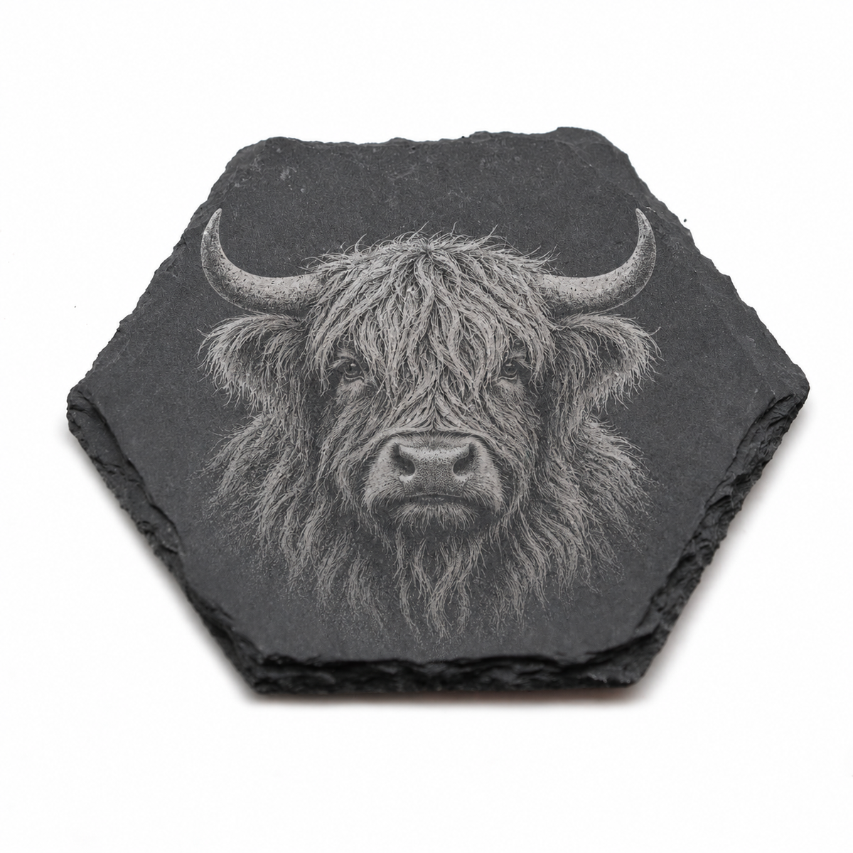 A hexagonal dark gray slate coaster featuring a detailed white and gray engraving of a Highland cow head, shown on a plain white background.
