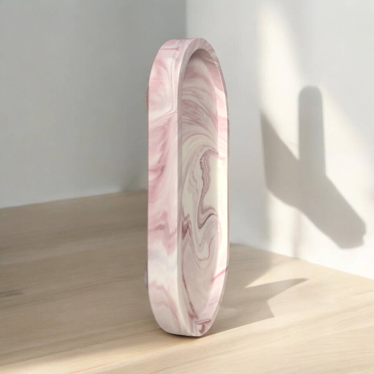 Handmade merlot marble Jesmonite oval tray stood on its edge, showing the swirled marble pattern in natural light, Croft & Cleo