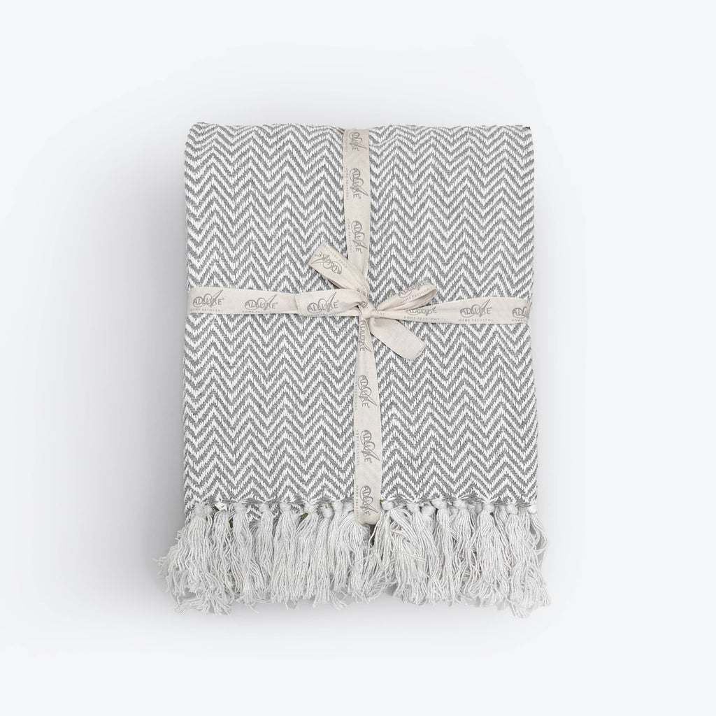 Moorland Herringbone Cotton Throw in Moss draped over a sofa arm, Croft & Cleo