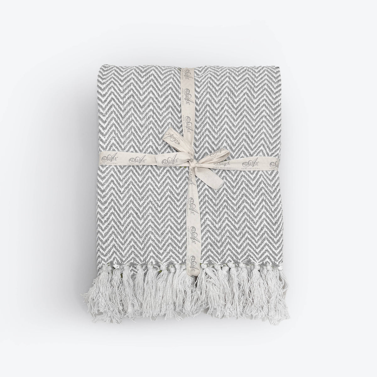 Moorland Herringbone Cotton Throw in Moss draped over a sofa arm, Croft & Cleo